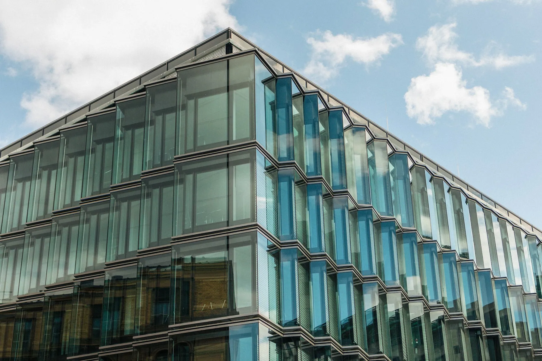 Modern glass office building beneath a cloudy sky