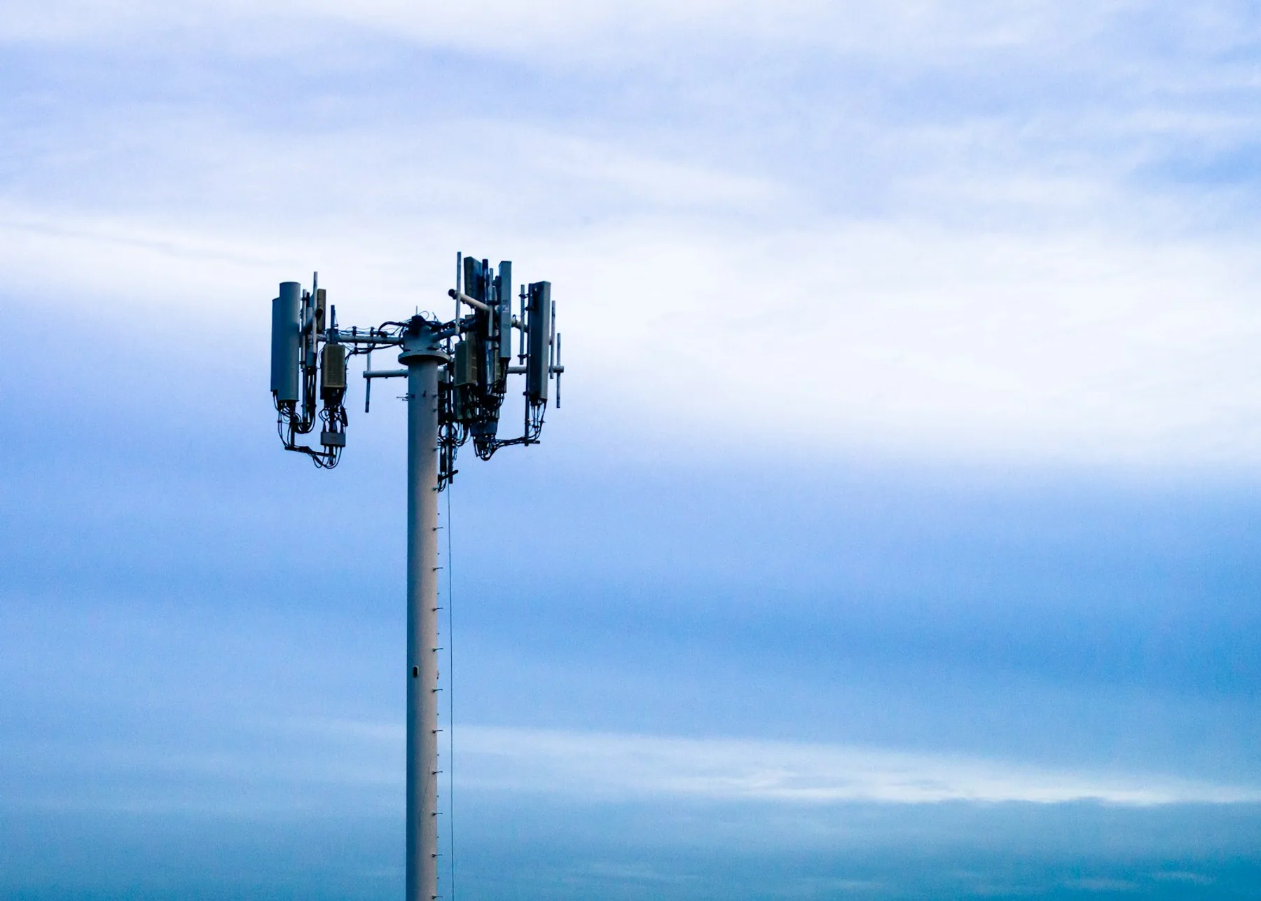 Cellular communications tower against a cloudy blue sky